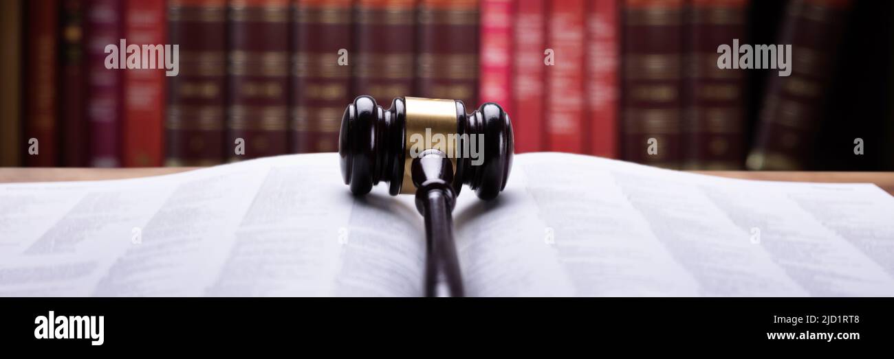 Nahaufnahme eines offenen Gesetz Buch und Holzhammer im Gerichtssaal Stockfoto