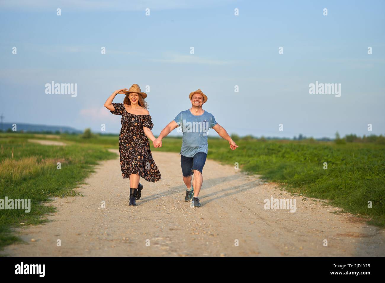 Glückliches gemischtes Rennpaar auf einer Landstraße bei Sonnenuntergang Stockfoto