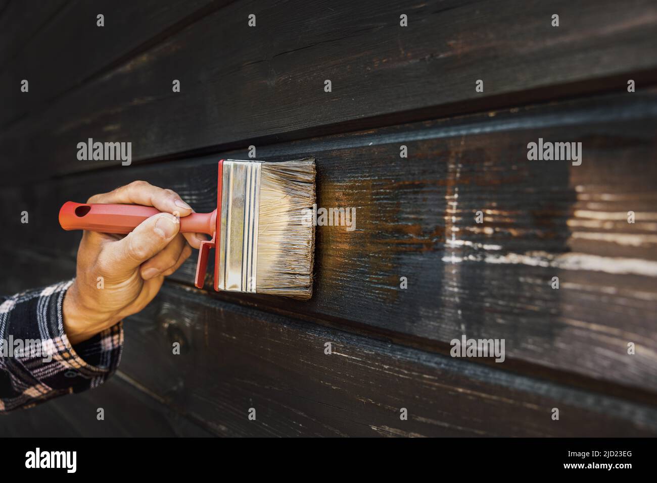 Hand mit Pinsel Wiederherstellung Farbe der alten Holzhaus Außenwand Stockfoto