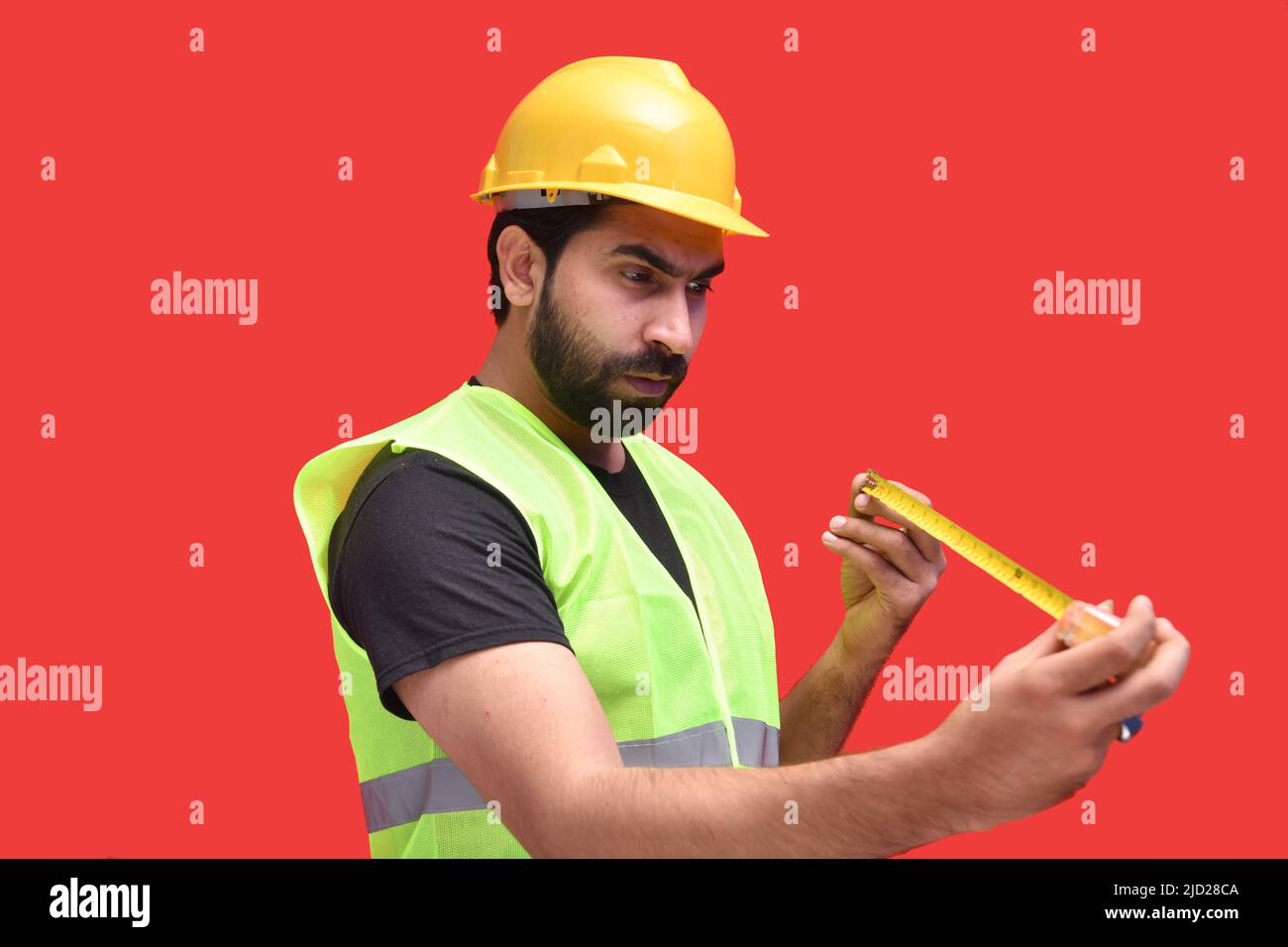 Bauarbeiter hält Zollband und misst die Größe mit Ausdruck posing Seite Stockfoto