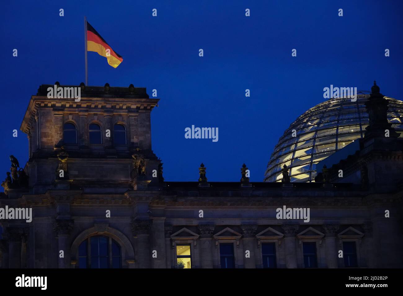 Nachtaufnahme des Reichstags in Berlin. Ein Fenster ist beleuchtet. Eine deutsche Flagge winkt im Wind. Berlin, Deutschland, 1.5.22 Stockfoto