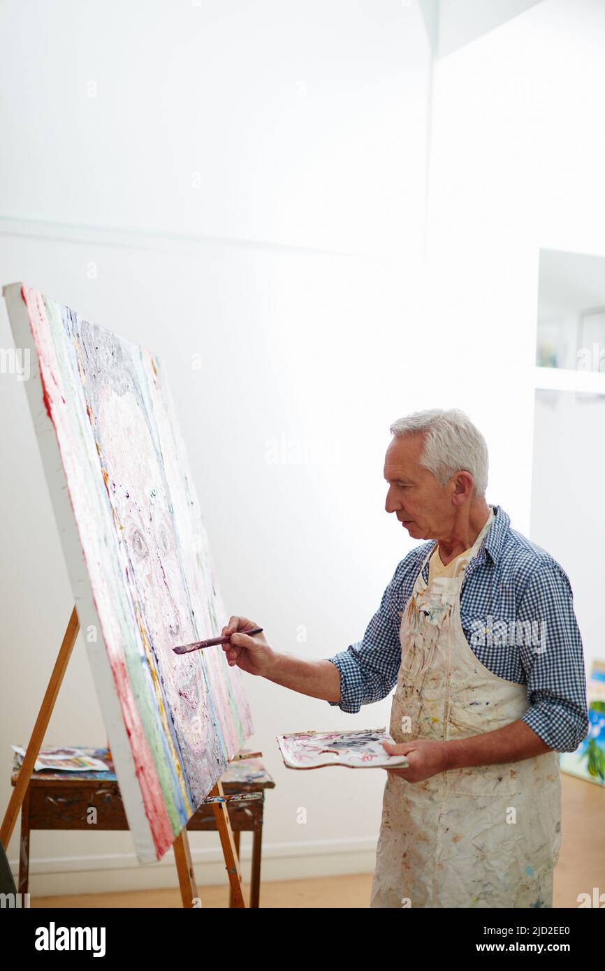 Kreativität ist Intelligenz, Spaß zu haben. Aufnahme eines älteren Mannes, der zu Hause an einem Gemälde arbeitet. Stockfoto