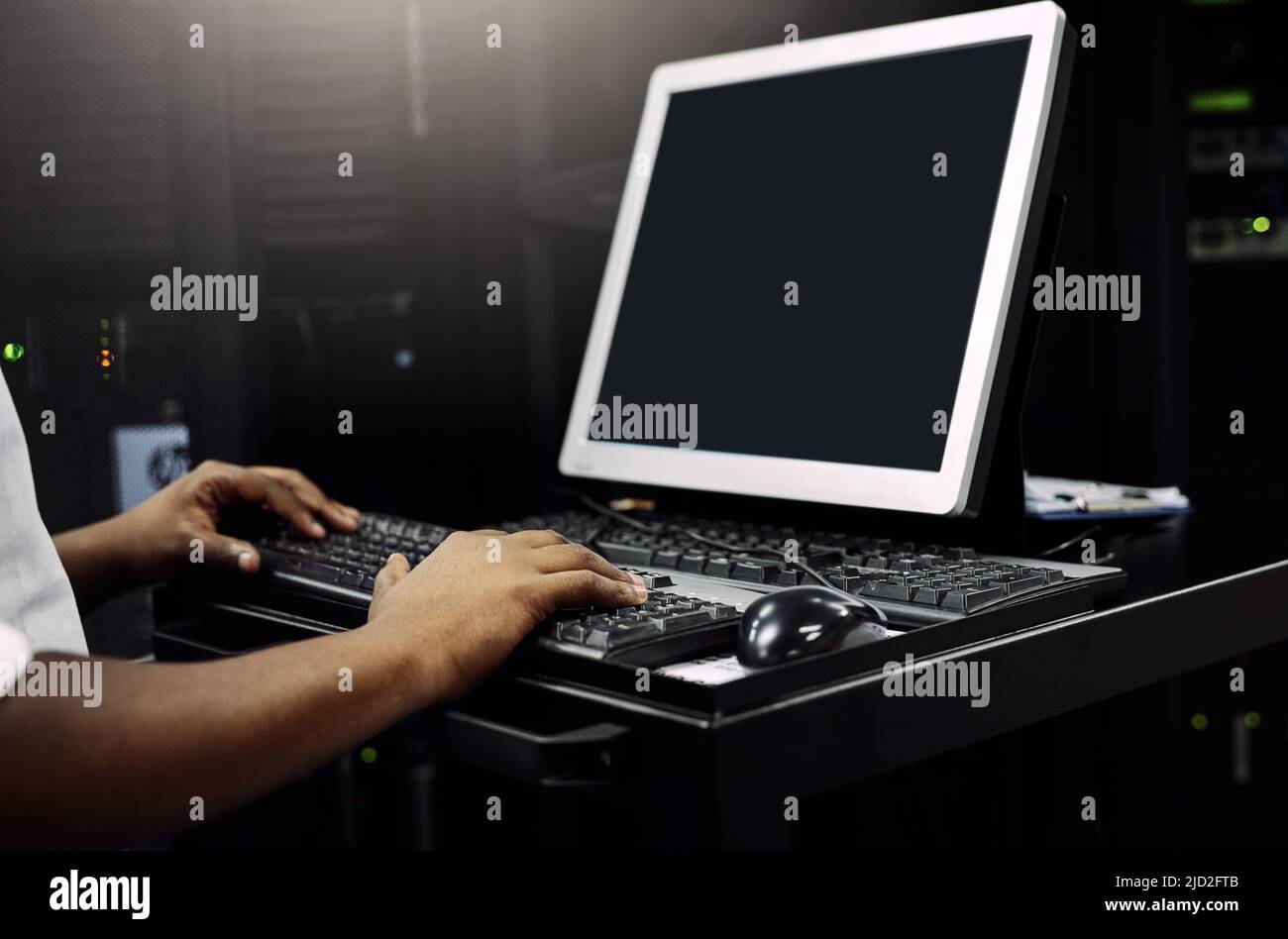 Jeder Server muss gründlich überprüft werden. Ausgeschnittene Aufnahme eines nicht erkennbaren IT-Technikers, der während der Arbeit in einem Rechenzentrum einen Computer verwendet. Stockfoto