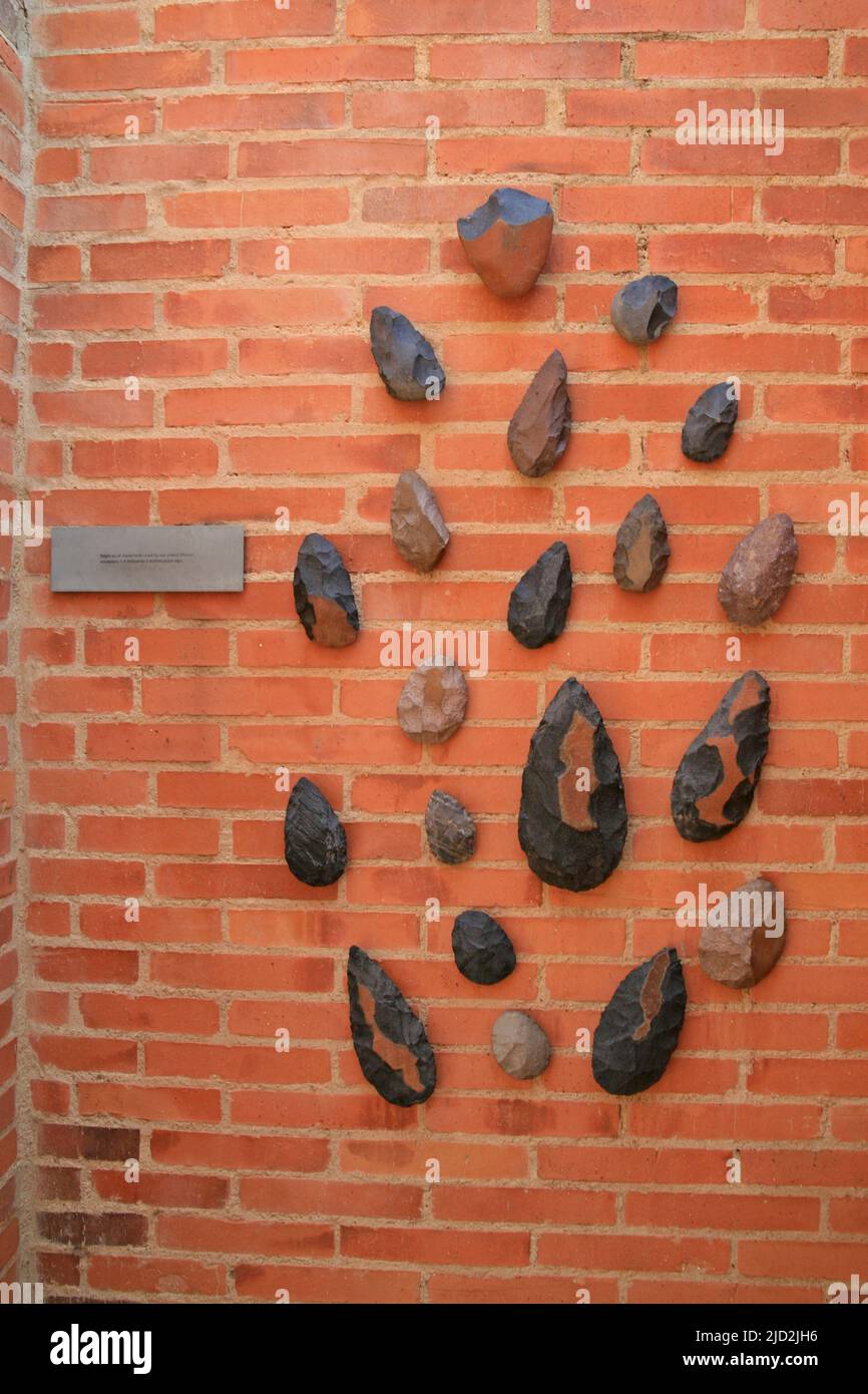 Repliken von Steinwerkzeugen, die von unseren ältesten afrikanischen Vorfahren vor 1,4 Millionen bis 2 Millionen Jahren auf einer Ziegelmauer in der Ausstellung, Apartheid Museum, Johanne, verwendet wurden Stockfoto