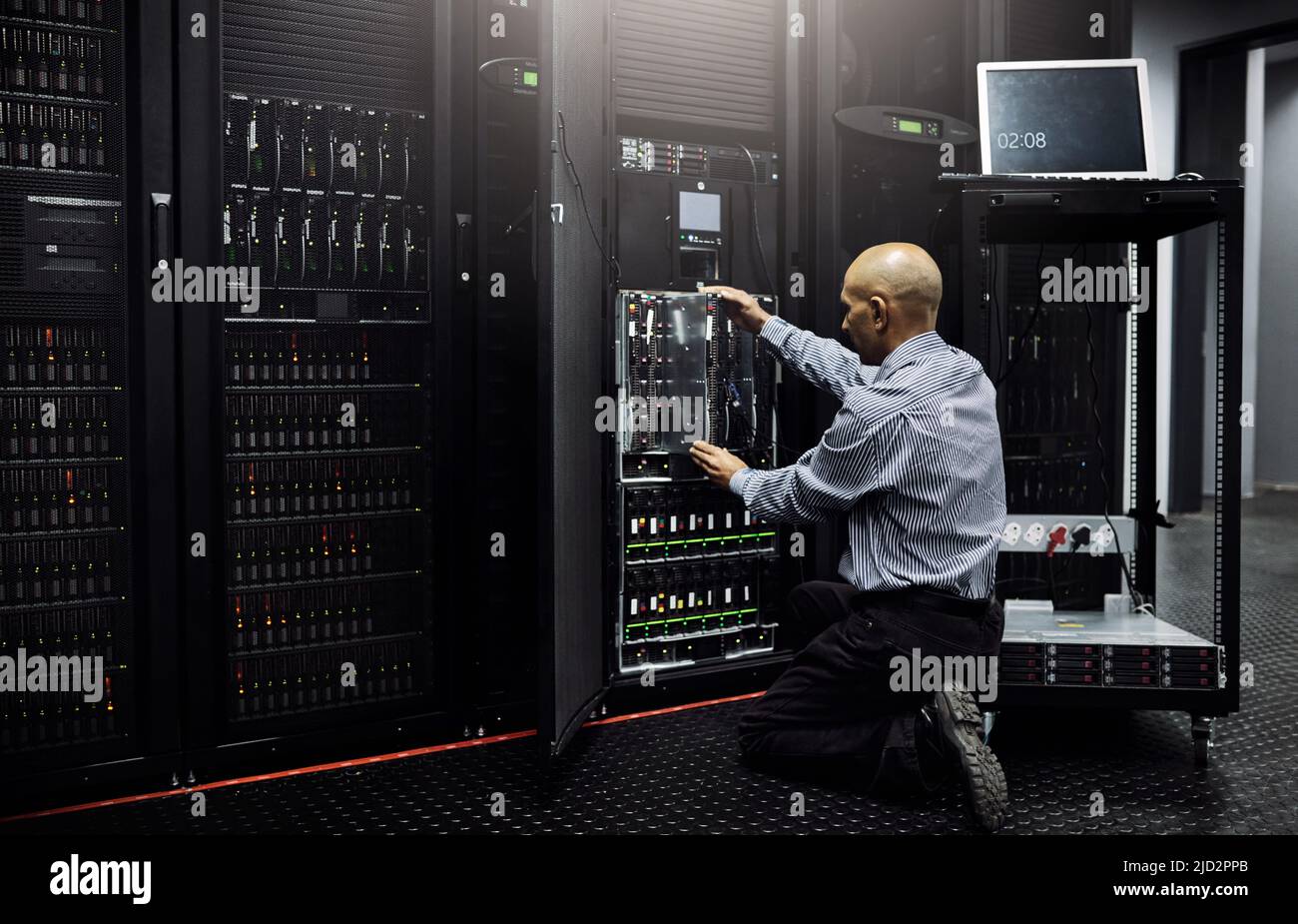 HES kennt sich gut mit allen Dingen AUS. Rückansicht eines IT-Technikers, der einen Computer in einem Rechenzentrum repariert. Stockfoto