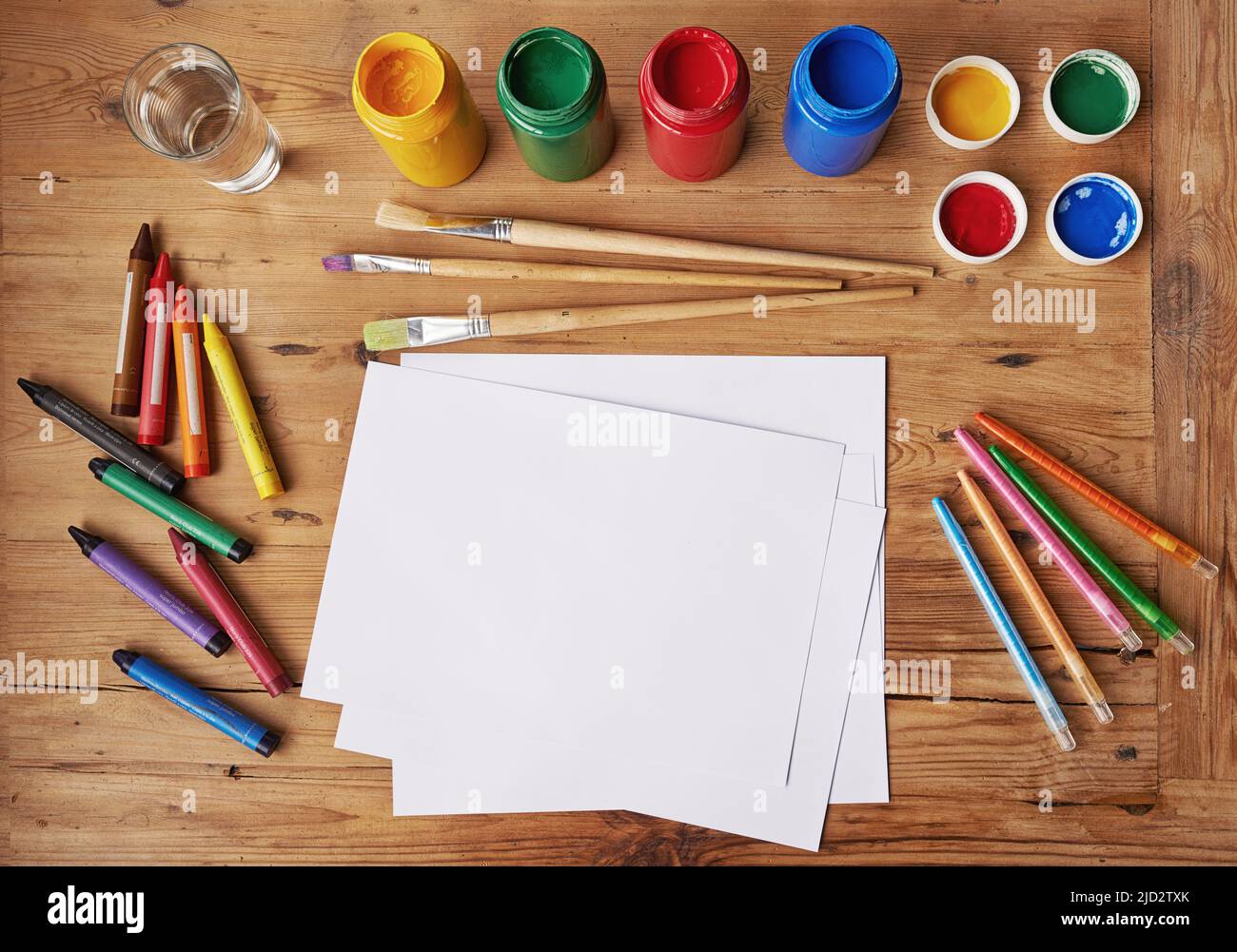 Kreativität geht nie aus dem Stil. Leeres weißes Papier mit Malutensilien und Bleistiften auf einem Holztisch. Stockfoto