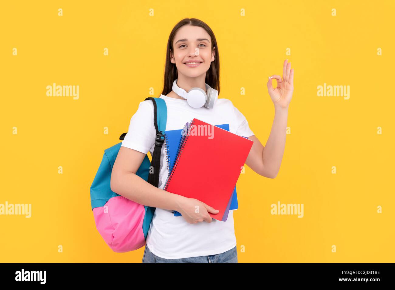 Positive Dame in Kopfhörer halten Copybook tragen Rucksack, zurück zur Schule Stockfoto