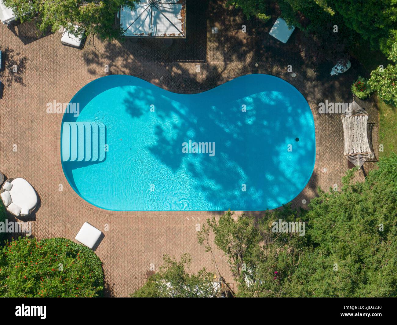 Luftaufnahme von einem Schwimmbad, Entspannung und Resort, Bänke und Sitzgelegenheiten. Hängematte. Wie man sich inmitten von Grün entspannen kann. Transparent und kristallin Stockfoto