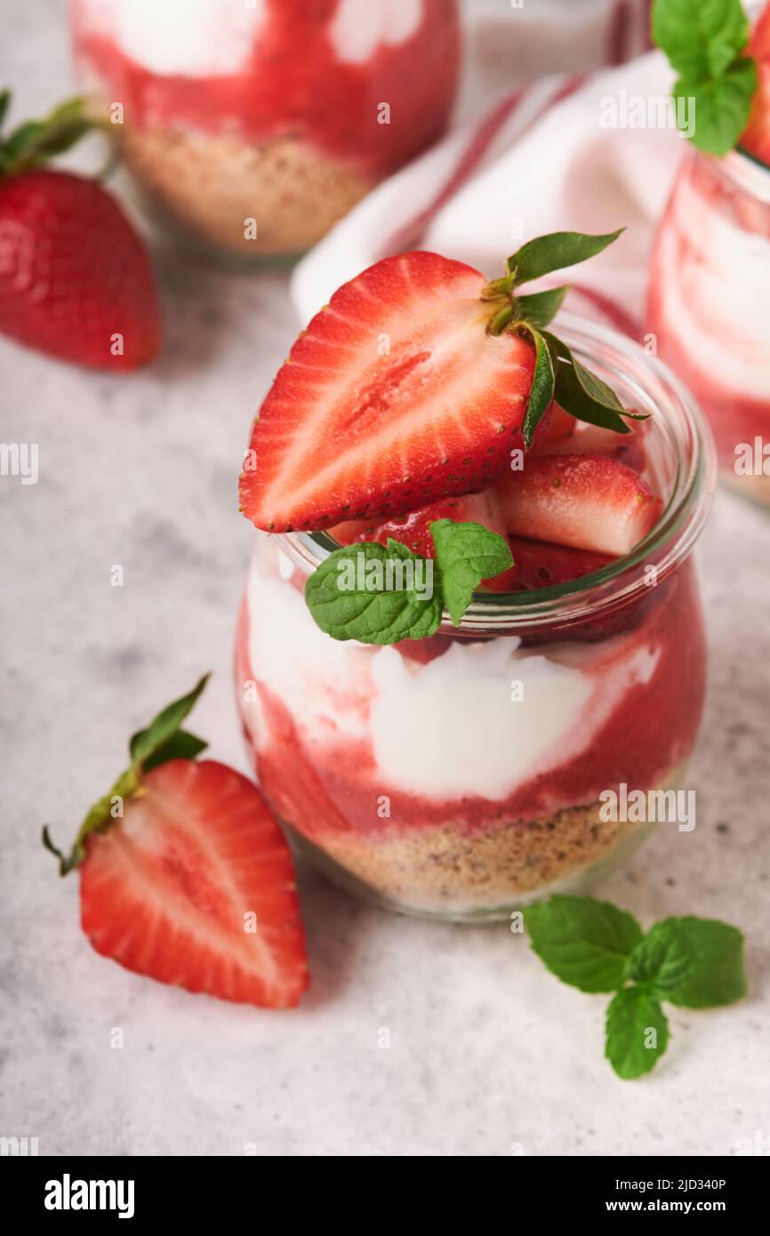 Erdbeerkäsekuchen. Käsekuchen oder Kleinigkeit mit Erdbeere im Glas auf altem grauen Beton Hintergrund Tischhintergrund. Käsekuchen ohne Backen. Abs Stockfoto