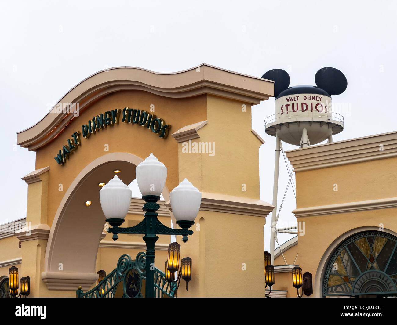 Paris, France - 04/05/2022: Wasserturm und Eingangsbogen zu den Walt Disney Studios in Disneyland Paris. Wolkiges Wetter. Menschen, die zum Tor gehen. Stockfoto
