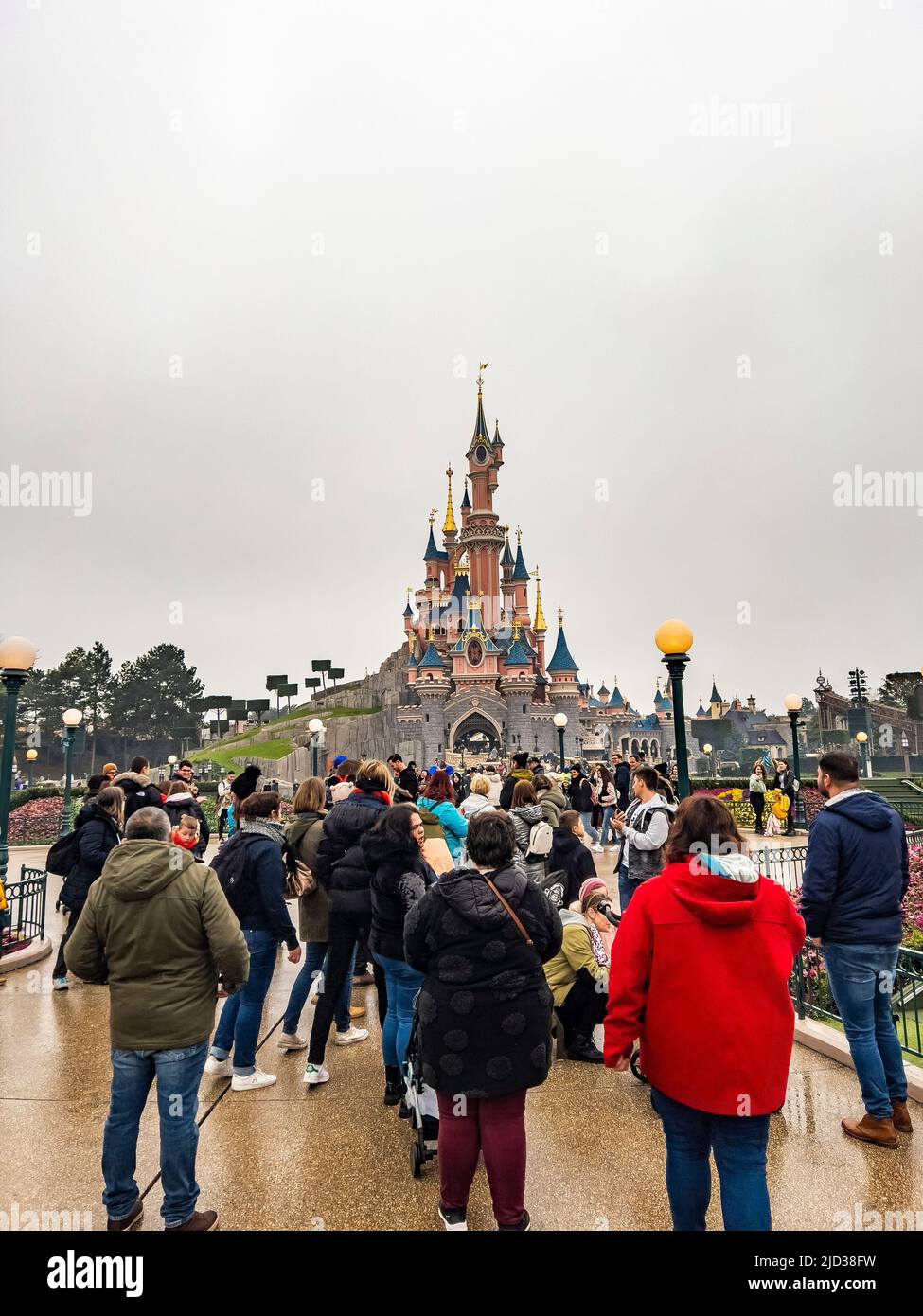 Paris, Frankreich - 04/05/2022: Menschen, die zu Fuß zum berühmten und ikonischen Gebäude der Disneyland Parks gehen. Dornröschenschloß bei bewölktem Wetter. Stockfoto