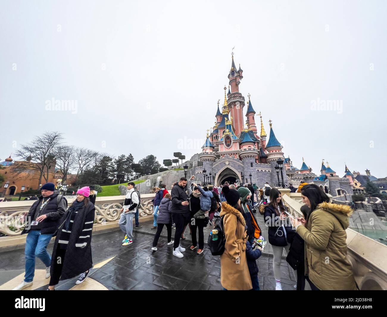 Paris, Frankreich - 04/05/2022: Menschen, die zu Fuß zum berühmten und ikonischen Gebäude der Disneyland Parks gehen. Dornröschenschloß bei bewölktem Wetter. Stockfoto