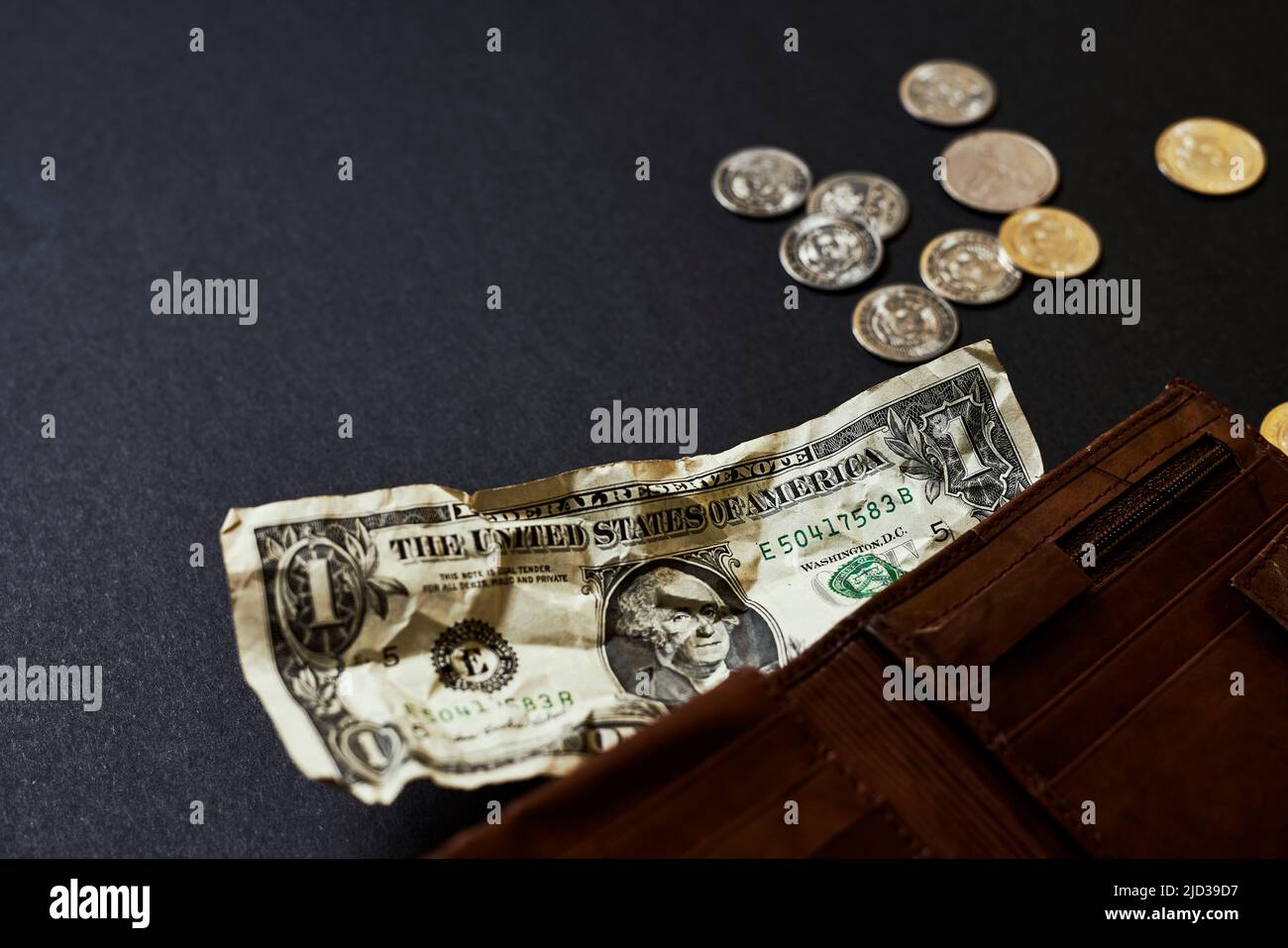 Eine einzige ein-Dollar-Rechnung in einer Ledertasche für Männer stellt Inflation, ein Währungskriegkonzept und die Situation der globalen Wirtschaftskrise dar. Geringe Schärfentiefe. Stockfoto