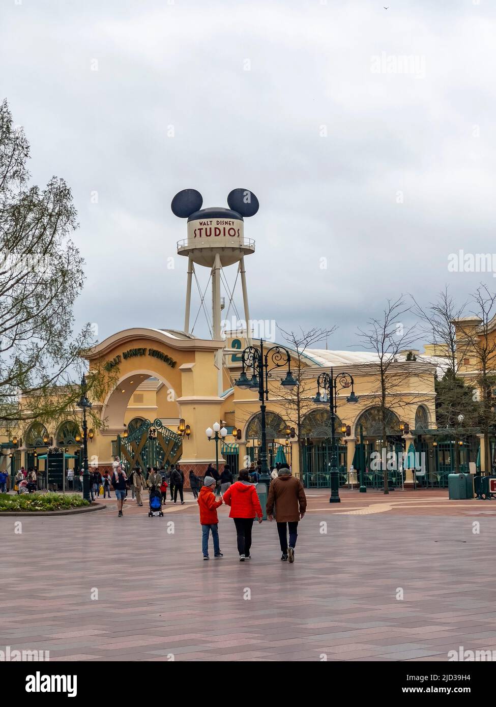 Paris, France - 04/05/2022: Familie mit Rückansicht. Menschen gehen. Wasserturm und Eingangsbogen zu den Walt Disney Studios in Disneyland Paris. Stockfoto