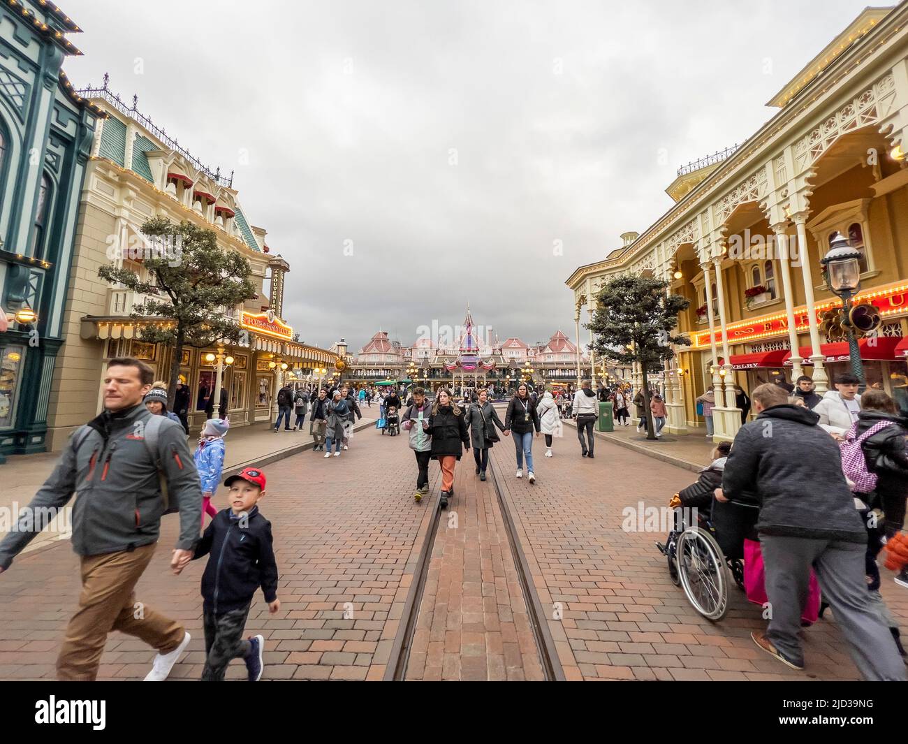 Paris, Frankreich - 04/05/2022: Vater hält Söhne an der Hauptstraße. Menschen, die zu Fuß zum berühmten und ikonischen Gebäude der Disneyland Parks gehen. Stockfoto
