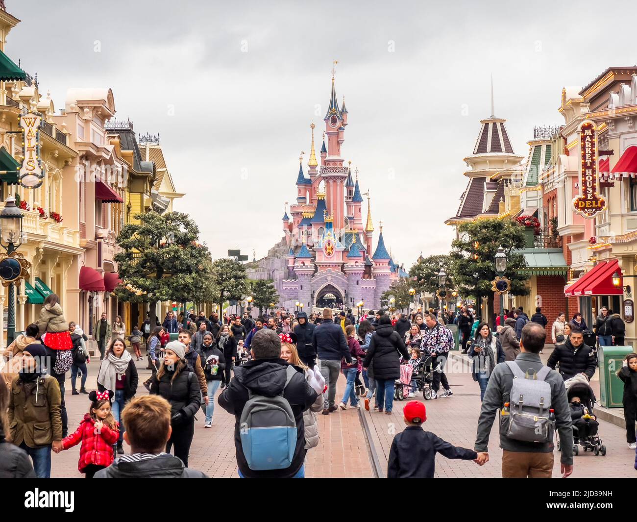 Paris, France - 04/05/2022: Dornröschenschloß bei bewölktem Wetter. Menschen, die zu Fuß zum berühmten und ikonischen Gebäude der Disneyland Parks gehen. Lustige Geschäfte Stockfoto