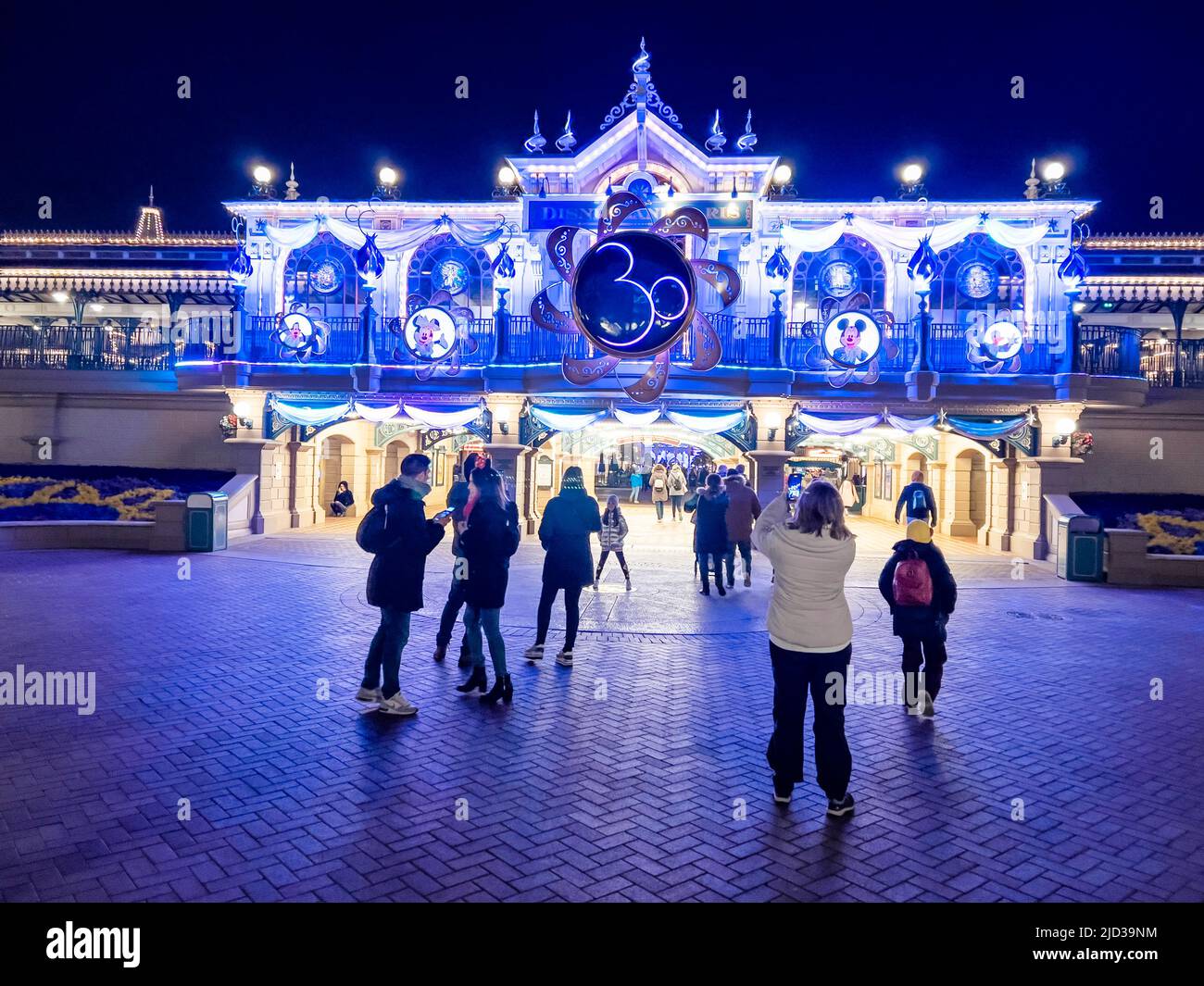 Paris, France - 04/05/2022: Farbenfroher Platz von Disneyland bei Nacht. Menschen, die herumlaufen. Stockfoto