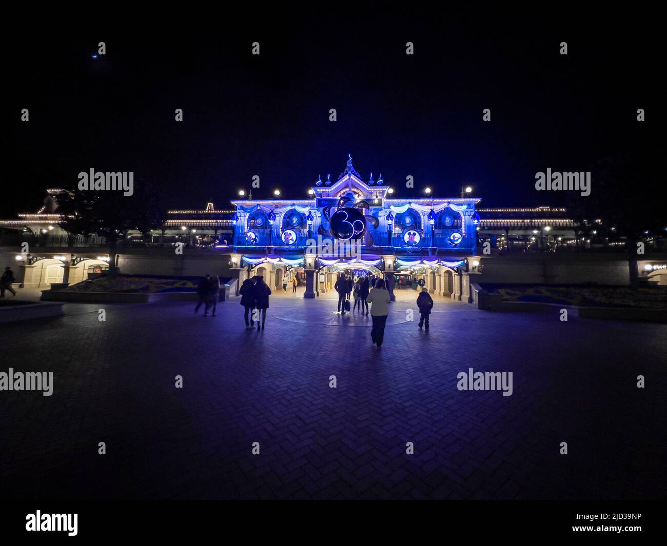 Paris, France - 04/05/2022: Farbenfroher Platz von Disneyland bei Nacht. Menschen, die herumlaufen. Stockfoto