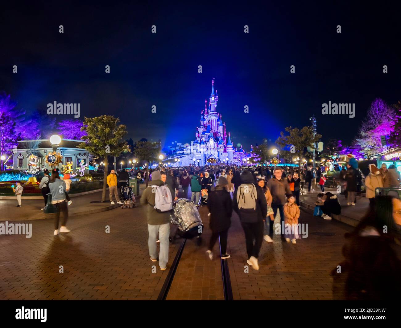 Paris, France - 04/05/2022: Farbenfroher Platz von Disneyland bei Nacht. Menschen, die herumlaufen. Stockfoto