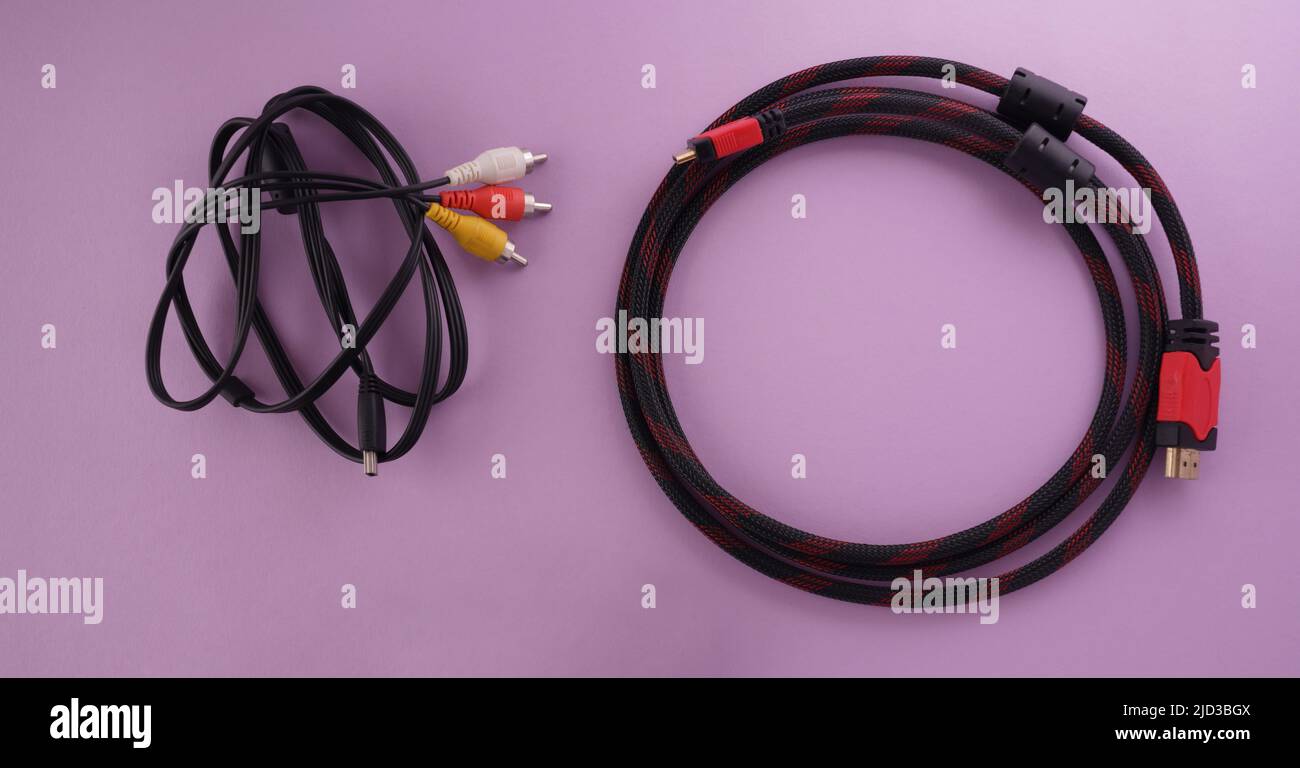 Draufsicht des HDMI-Kabels im Vergleich zum analogen RCA-Anschluss auf violettem Hintergrund Stockfoto