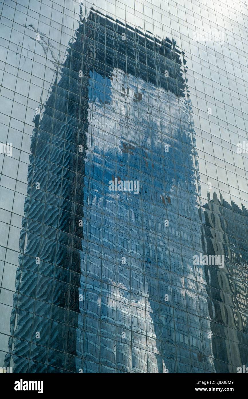 Spiegelung eines Wolkenkratzers, der an einem sonnigen Tag mit Wolken in einem Geschäftsviertel im Zentrum Nordamerikas im Bau ist. Stockfoto