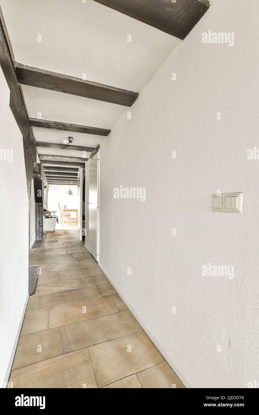 Ein kompakter, heller Korridor mit weißen Wänden und Fliesenboden Stockfoto