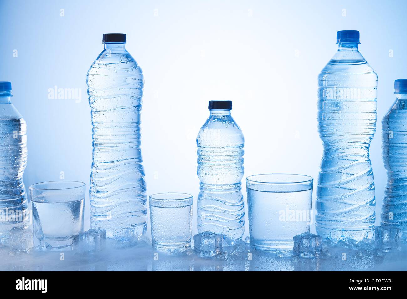 Verschiedene Arten von Eis-Mineralwasser-Flasche mit Gläsern Wasser auf blauem Hintergrund. Stockfoto