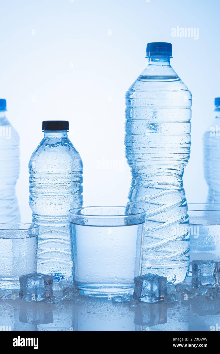 Verschiedene Arten von Eis-Mineralwasser-Flasche mit Gläsern Wasser auf blauem Hintergrund. Vertikales Format. Stockfoto