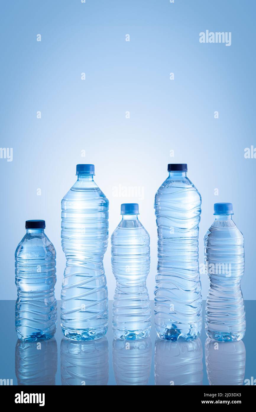 Sammlung von Wasserflaschen isoliert auf blauem Hintergrund mit Kopierraum. Vertikales Format. Stockfoto