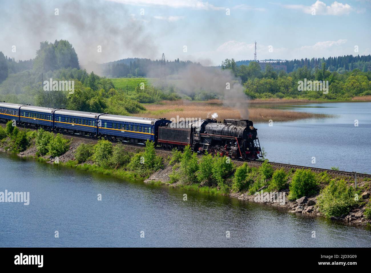 RUSKEALA, RUSSLAND - 11. JUNI 2022: Dampflokomotive mit einem alten Touristenzug 'Ruskeala Express' auf dem Damm des Sees. Karelien Stockfoto