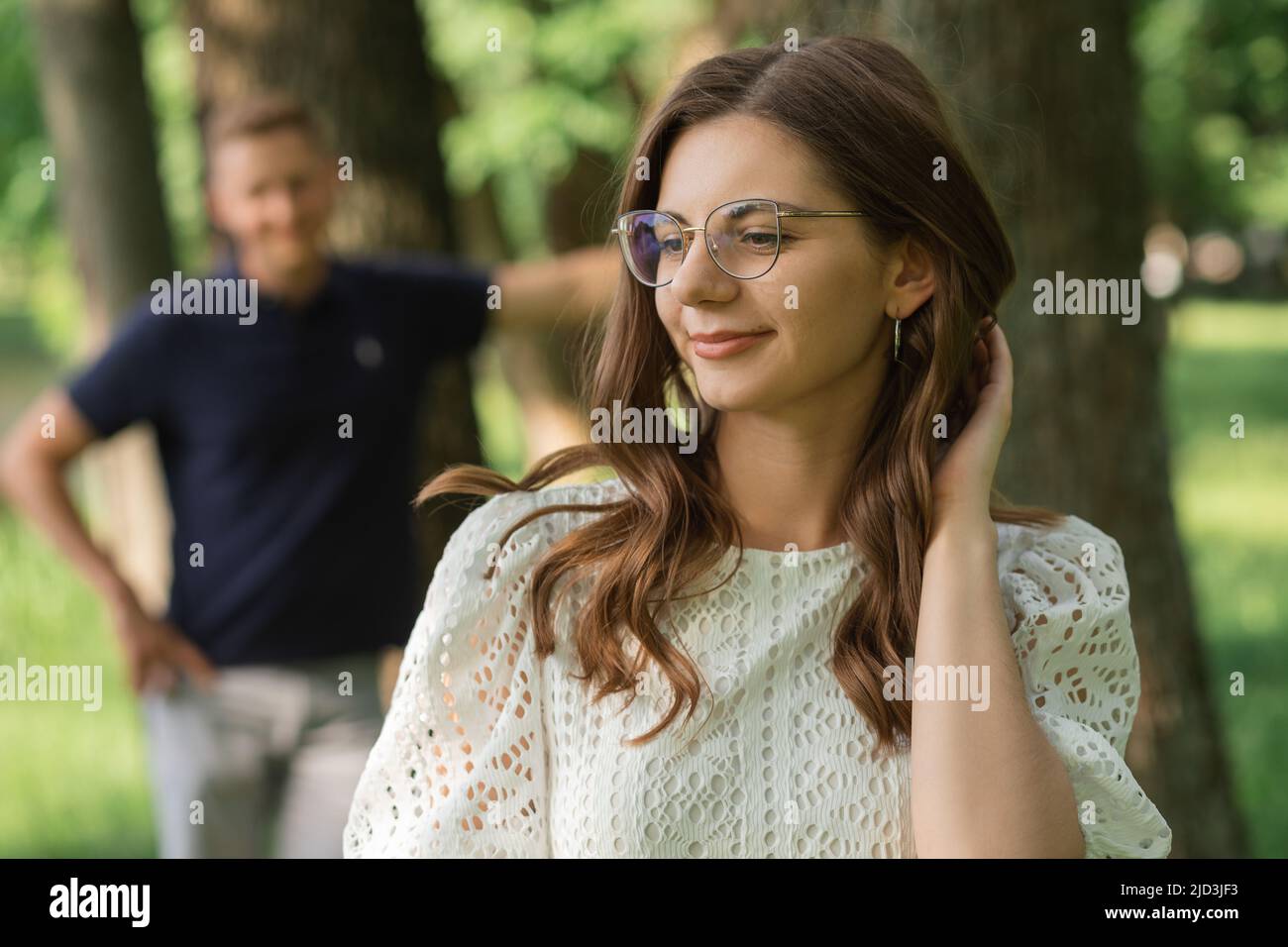 Defokussieren Mann auf Frau im Park unter Bäumen, glückliche Menschen, die Spaß am Sommertag haben, Paar verliebt. Romantischer Moment Stockfoto