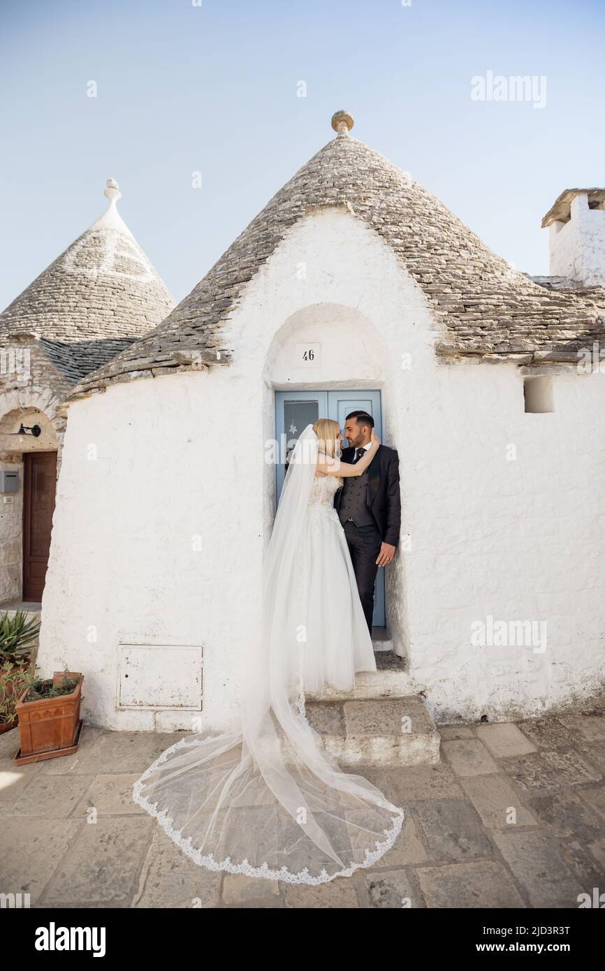 Vertikales Porträt ein frohes romantisches Ehepaar, eine blonde Frau in weißem Kleid und ein schwarzhaariger Mann in Smoking, Italien Stockfoto
