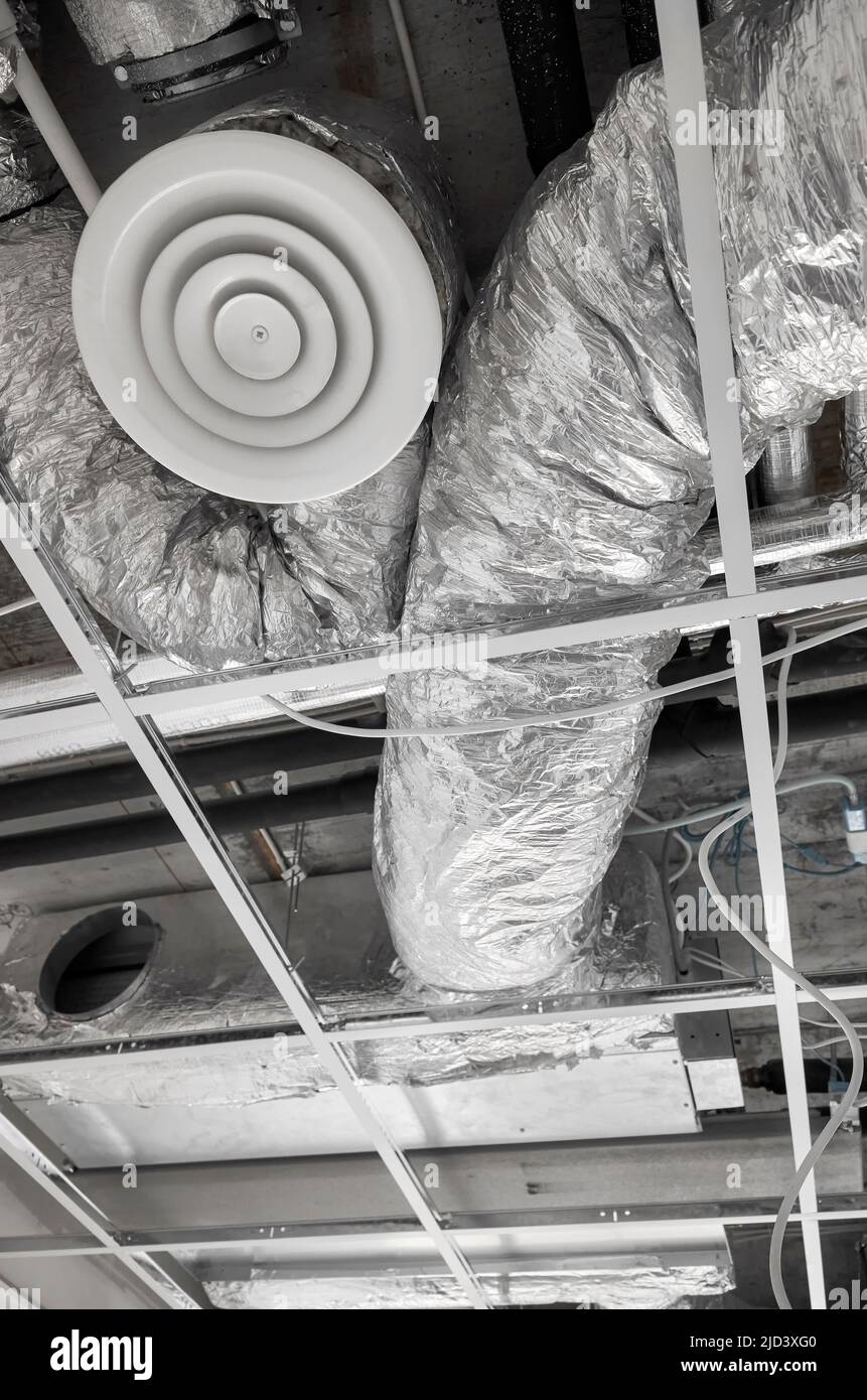 Belüftungssystem mit Rohren aus silbernem Dämmmaterial in abgehängter Decke während der Renovierung. Stockfoto