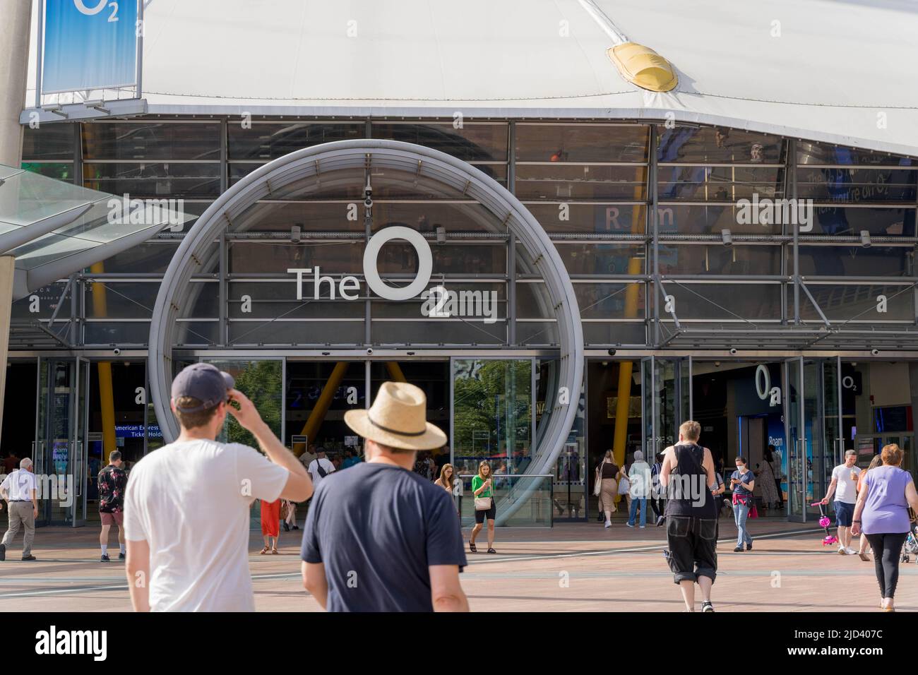 Menschen in T-Shirt gehen zum O-Ring gerahmten Eingang zur O2 Arena auf der nördlichen Greenwich-Halbinsel London England Großbritannien Stockfoto