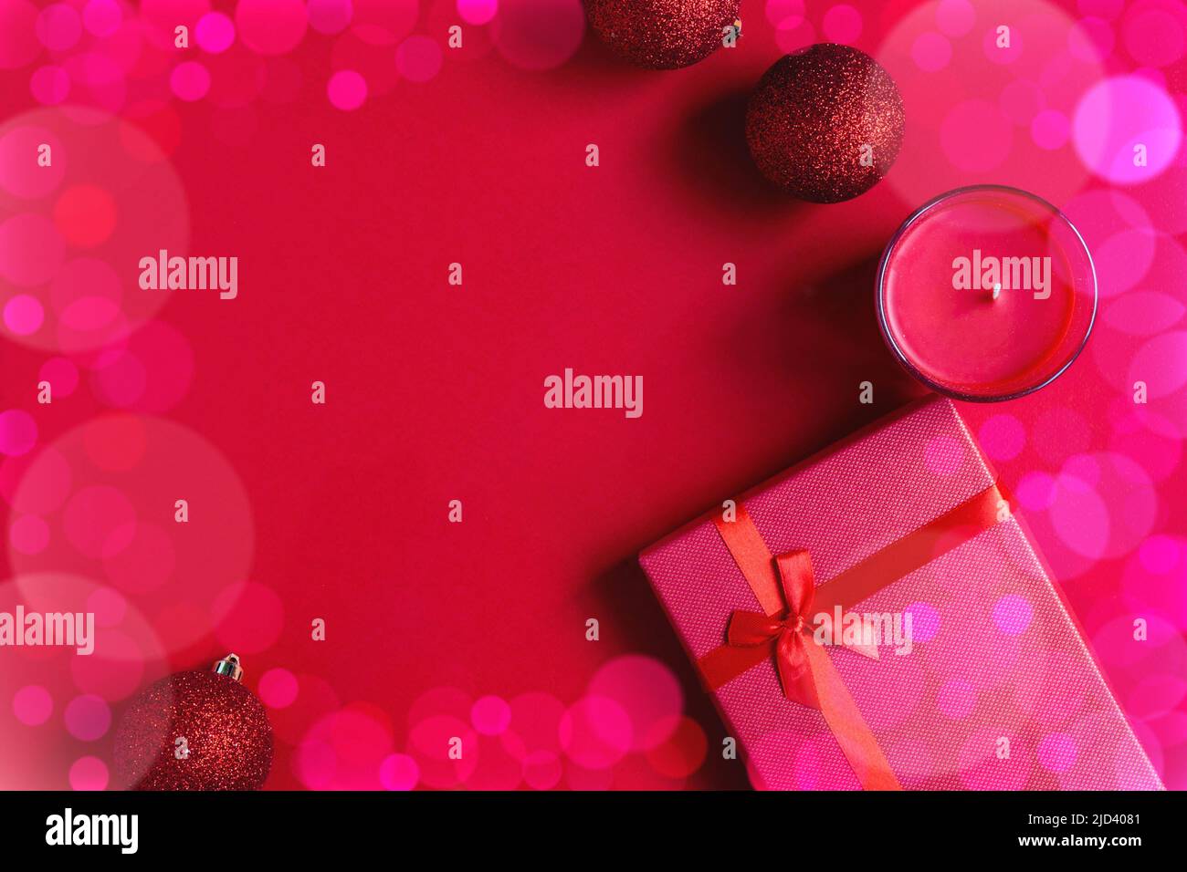 Helle schöne Geschenkbox und Kerzen und Weihnachtskugeln auf rotem Hintergrund zusammen mit Weihnachtslichtern und Bokeh. Tolles Design mit Platz für Kopien. Stockfoto