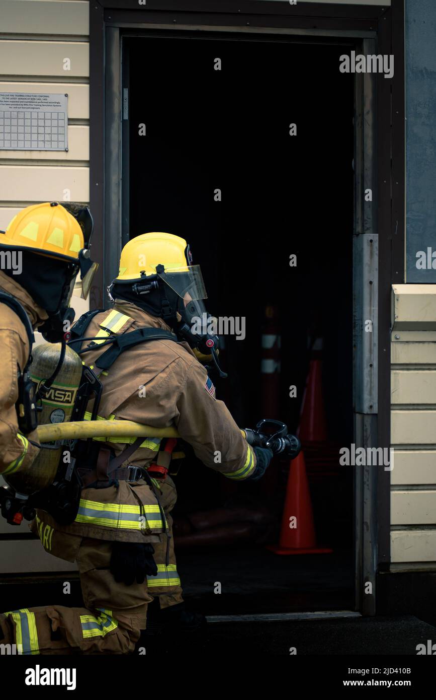 Mitglieder der 110. Civil Engineering Squadron, Battle Creek Air National Guard Base, Michigan, trainieren zusammen mit lokalen japanischen Feuerwehrleuten während des 110 CES's Deployment for Training (DFT) mit einem simulierten Gebäudebrand auf der Yakota Air Base, Japan, 14. Juni 2022. Das DFT-Programm bietet wertvolle Schulungsmöglichkeiten, die normalerweise nicht in Heimstationen-Szenarien verfügbar sind, und ermöglicht es Airmen, an Geräten zu trainieren, die sie wahrscheinlich während eines Einsatzes betreiben, aber möglicherweise nicht an ihrem Heimatstandort haben. (USA Foto der Air National Guard von Senior Airman Ryan Bishop) Stockfoto