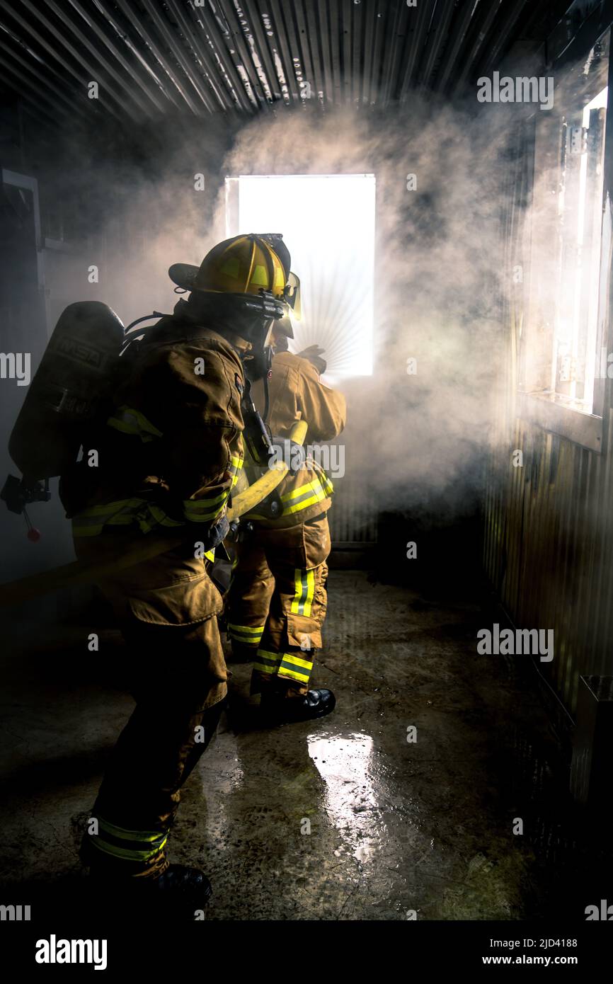 Mitglieder der 110. Wing Civil Engineering Squadron, Battle Creek Air National Guard Base, Michigan, trainieren zusammen mit lokalen japanischen Feuerwehrleuten während des Einsatzkampfes der CE Squadron (DFT) mit einem simulierten Gebäudebrand auf der Yakota Air Base, Japan, 14. Juni 2022. Das DFT-Programm bietet wertvolle Schulungsmöglichkeiten, die normalerweise nicht in Heimstationen-Szenarien verfügbar sind, und ermöglicht es Airmen, an Geräten zu trainieren, die sie wahrscheinlich während eines Einsatzes betreiben, aber möglicherweise nicht an ihrem Heimatstandort haben. (USA Foto der Air National Guard von Senior Airman Ryan Bishop) Stockfoto