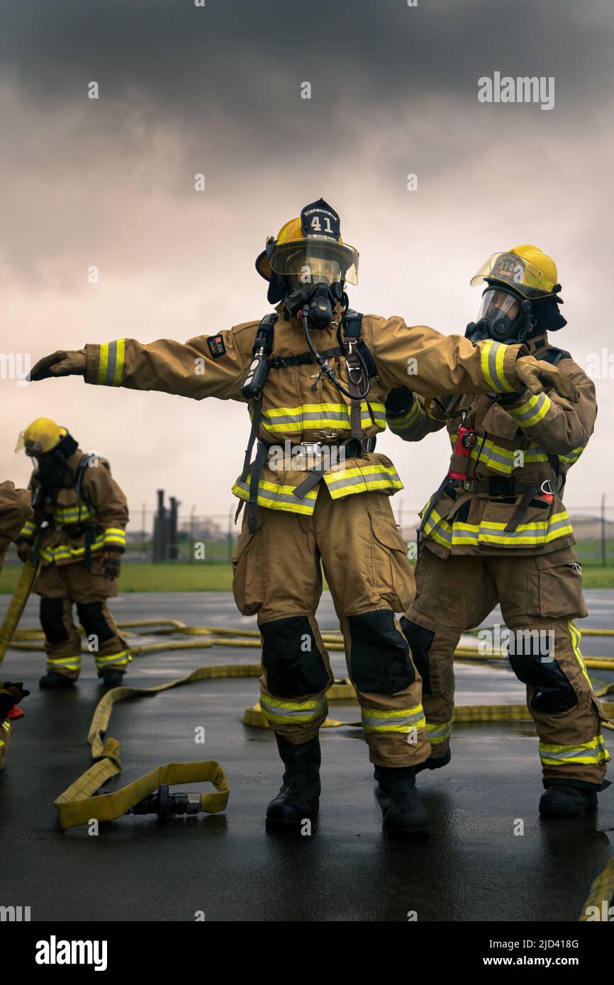 Mitglieder der 110. Wing Civil Engineering Squadron trainieren zusammen mit lokalen japanischen Feuerwehrleuten während des Einsatzverfahrens für Training (DFT) des CE Squadron mit einem simulierten Gebäudebrand auf dem Yakota Air Base, Japan, 14. Juni 2022. Das DFT-Programm bietet wertvolle Schulungsmöglichkeiten, die normalerweise nicht in Heimstationen-Szenarien verfügbar sind, und ermöglicht es Airmen, an Geräten zu trainieren, die sie wahrscheinlich während eines Einsatzes betreiben, aber möglicherweise nicht an ihrem Heimatstandort haben. (USA Foto der Air National Guard von Senior Airman Ryan Bishop) Stockfoto