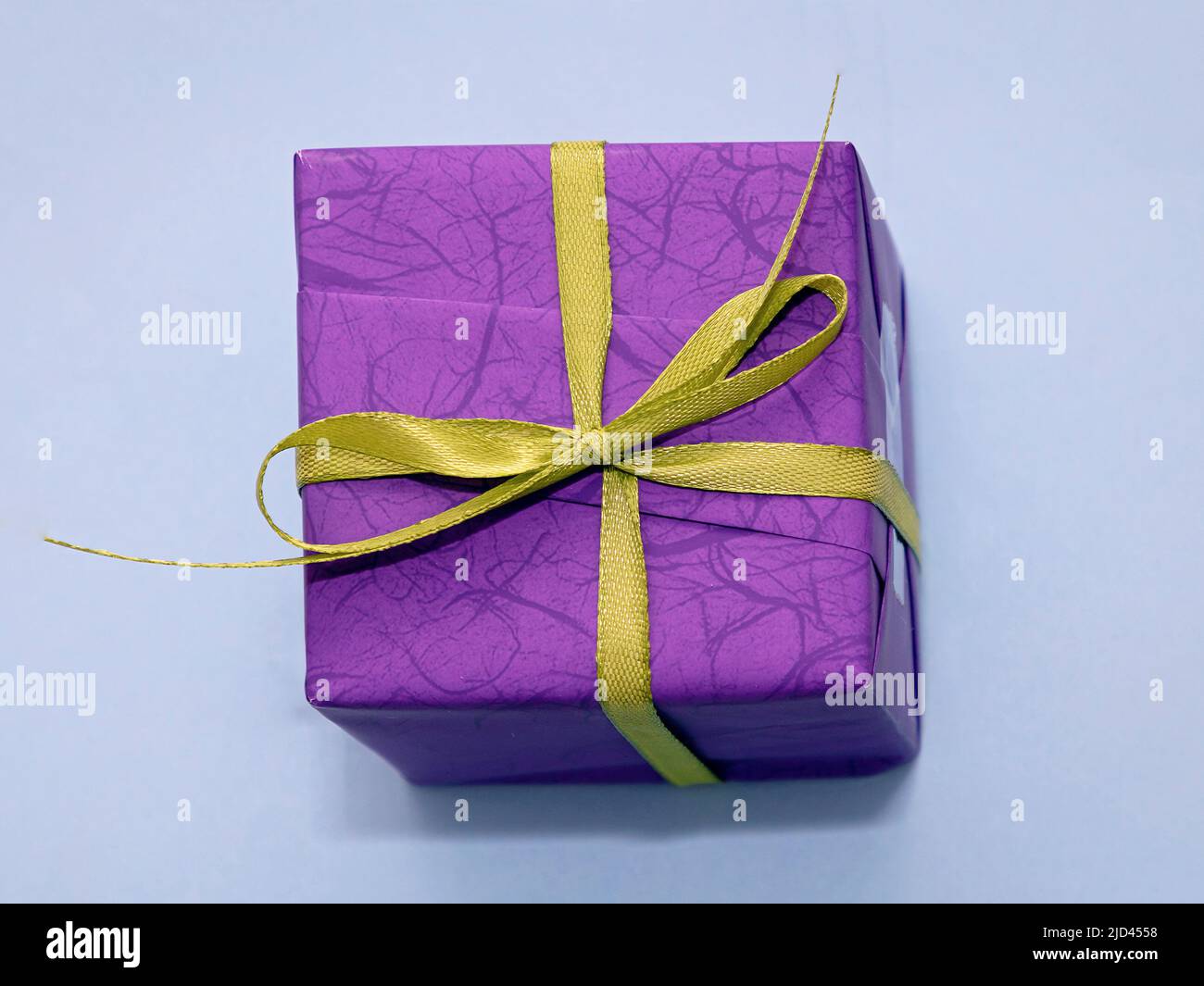 Dekorative lila Geschenkbox mit grüner Schleife auf blauem Hintergrund Stockfoto
