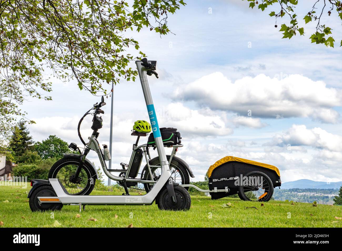 Everett, WA - USA -06-04-2022: Elektroroller im Vordergrund und Utility Moped Bike mit Burley Cargo Trailer im Hintergrund, zwei alternative Transpo Stockfoto