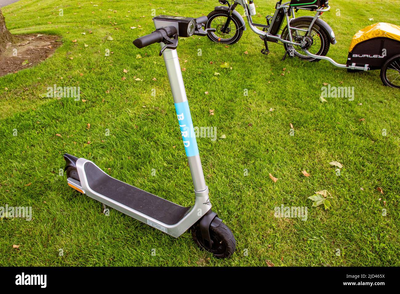 Everett, WA - USA -06-04-2022: Elektroroller im Vordergrund und Utility Moped Bike mit Burley Cargo Trailer im Hintergrund, zwei alternative Transpo Stockfoto