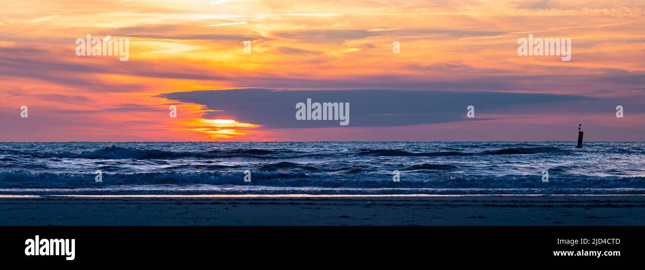 Panoramablick auf einen farbenfrohen Sonnenuntergang über der Brandung des Meeres Stockfoto