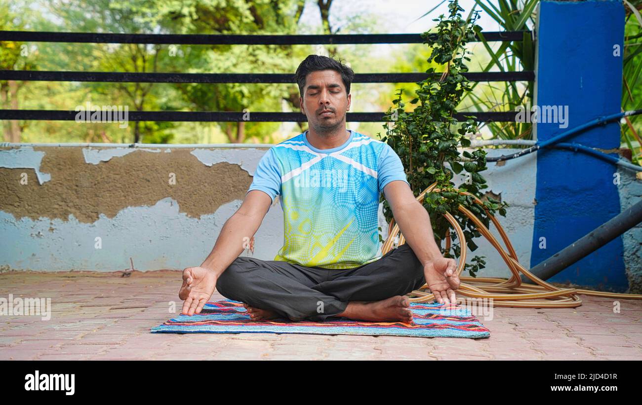 Schöner sportlicher indischer junger Mann, der zu Hause trainiert. Yoga-Pose sitzend. Ruhig und glücklich Stockfoto