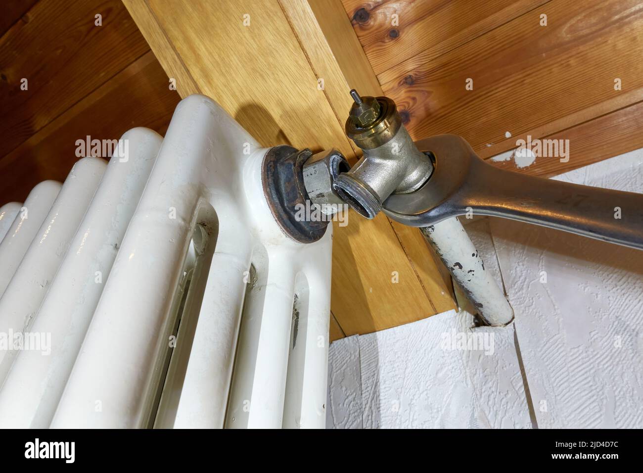 Das alte Thermostatventil des Kühlers austauschen. Der Gabelschlüssel entfernt das Bauteil aus dem Heizelement. Modernisierung von Heizsystemen. Ansicht von oben. Stockfoto