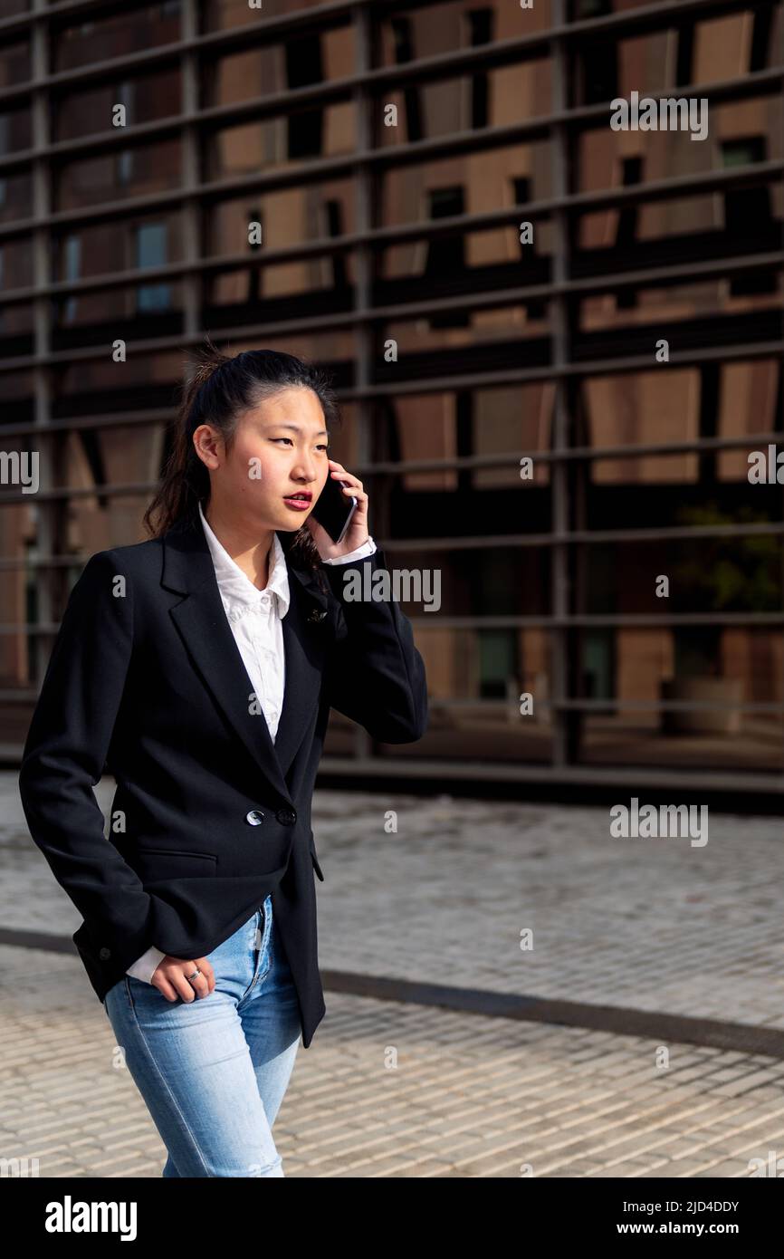 Junge asiatische Geschäftsfrau im Gespräch am Telefon Stockfoto