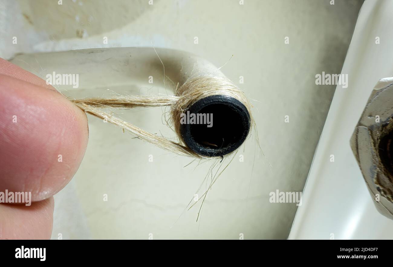 Heizrohr mit Hanf abdichten. Thermostatventil an der Heizkörperheizung austauschen. Von Hand reparierte Schraubverbindung in der Installation. Stockfoto Heizrohr mit Hanf abdichten. Thermostatventil an der Heizkörperheizung austauschen. Von Hand reparierte Schraubverbindung in der Installation. Stockfoto