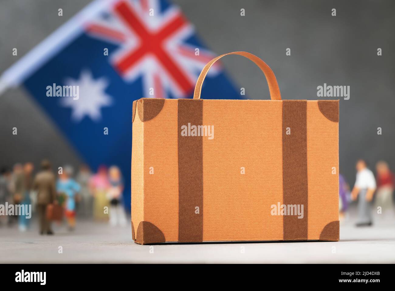 Pappkoffer, Plastikspielzeug Menschen und eine Flagge auf abstraktem Hintergrund, ein Konzept zum Thema Umzug oder Einwanderung nach Australien Stockfoto