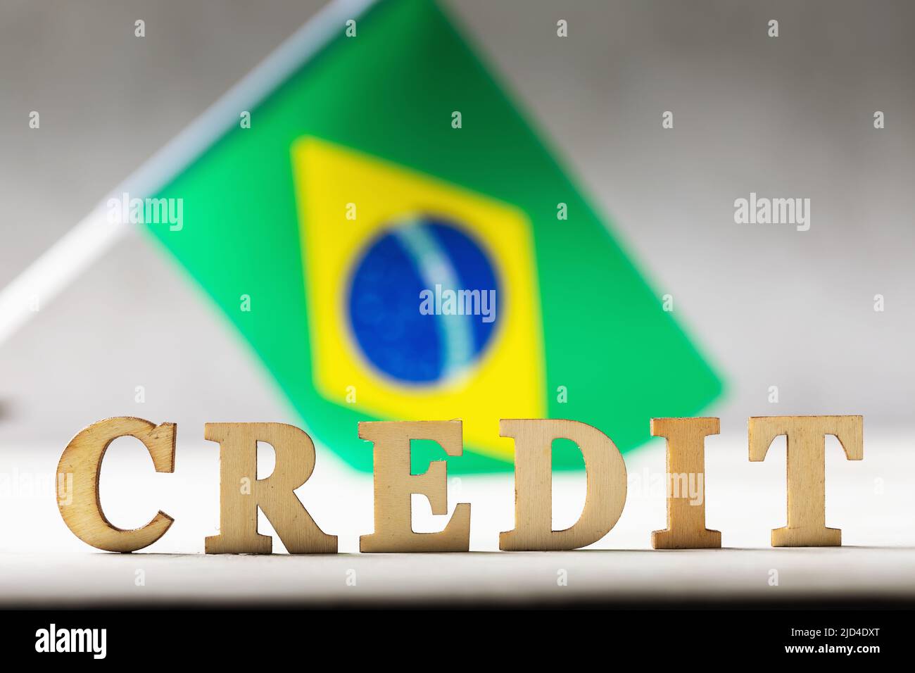 Text aus Holzbuchstaben und die Flagge Brasiliens auf einem abstrakten Hintergrund, das Konzept der Verwendung von Krediten im Land. Stockfoto