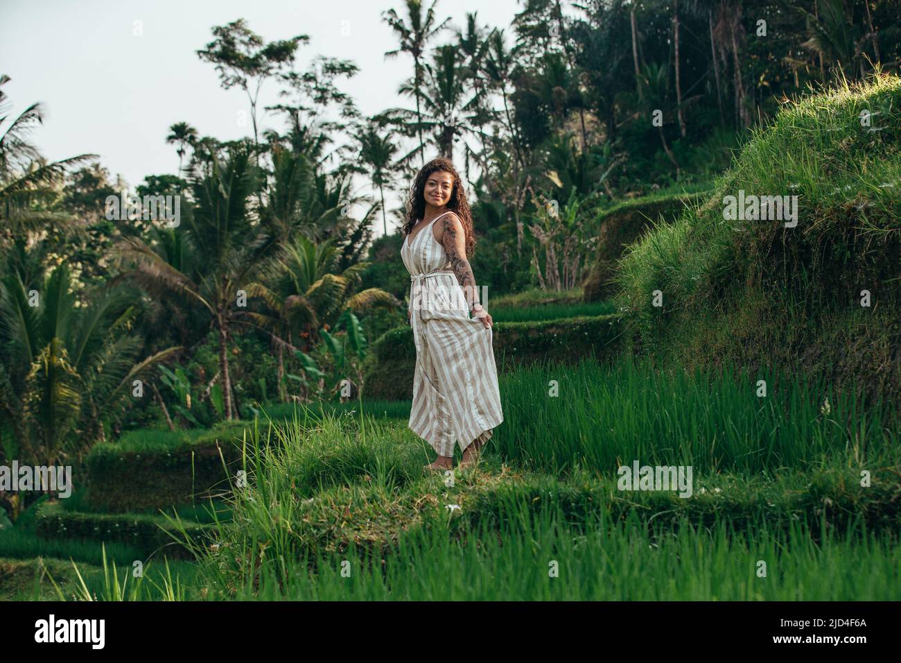 Junge glückliche hispanische Frau in weißem Strampelanzug auf der Tegalalalang Reisfeld-Terrasse in Ubud Bali Stockfoto