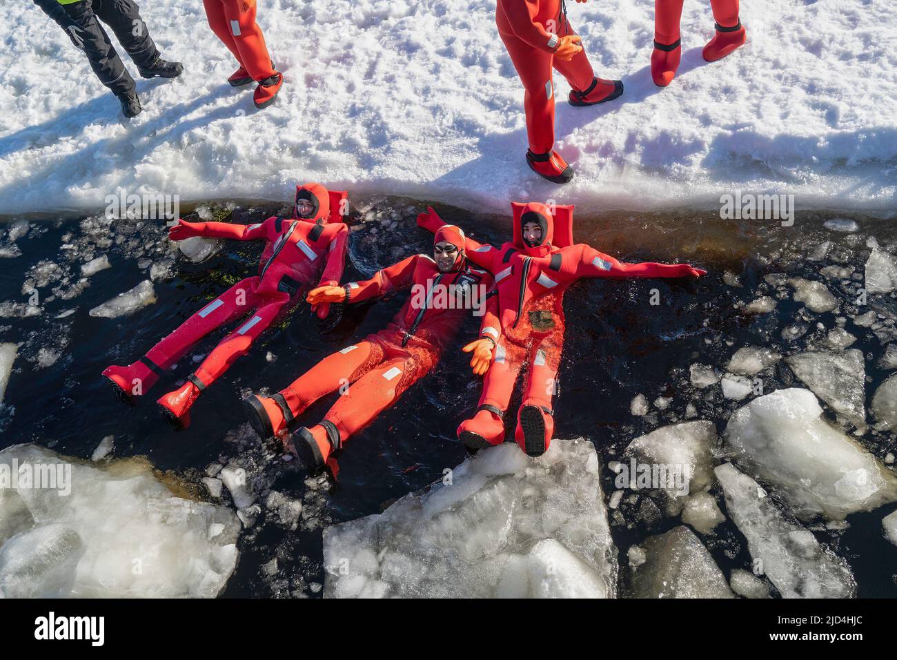 Rovaniemi, Finnland - 21.. März 2022: Eine Gruppe von Touristen schwimmt im gefrorenen Wasser der auftauenden ostsee mit Isolieranzügen. Stockfoto
